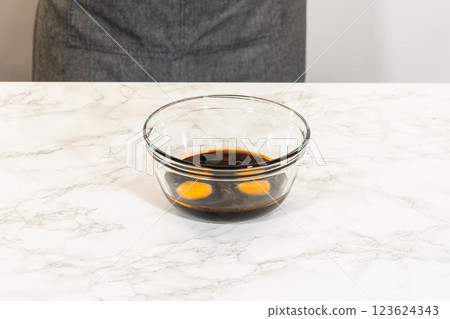 Wet ingredients, including molasses and eggs, combined in a mixing bowl for Chocolate Gingerbread Cookie Dough. This mixture provides the dough with richness and moisture. Wet ingredients, including molasses and eggs, combined in a mixing bowl for Chocolate Gingerbread Cookie Dough. This mixture provides the dough with richness and moisture. 123624343