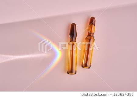 An ampoule with a medical product or cosmetic product on a pink background. 123624395