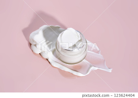 An open jar of cream with its texture on a pink background. An open jar of cream with its texture on a pink background. 123624404
