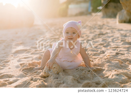 Beautiful girl in outdoor with sunset light. Child in pink dress on sandy beach. Beautiful girl in outdoor with sunset light. Child in pink dress on sandy beach. 123624724