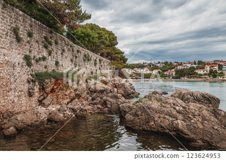 Serene coastal view showcasing rugged rocks and historic stone wall by the sea Serene coastal view showcasing rugged rocks and historic stone wall by the sea 123624953