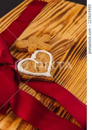 Iced gingerbread cookies on a wooden plate with red ribbon 123624993