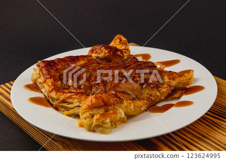 Flaky pastry dessert drizzled with warm caramel sauce on a wooden platter Flaky pastry dessert drizzled with warm caramel sauce on a wooden platter 123624995