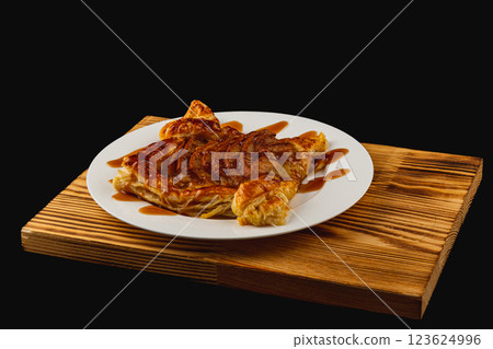 Delicious sweet pastry topped with caramel sauce served on a wooden platter 123624996