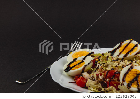 Delicious salad with eggs and fresh vegetables presented on a dark background 123625003