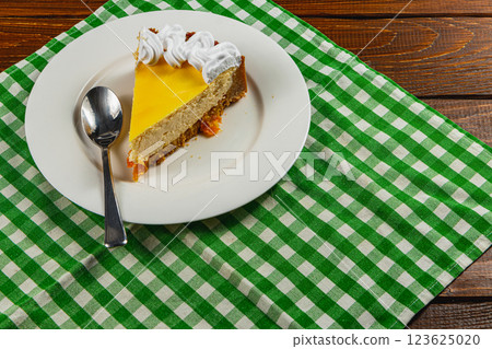 Delightful tropical cheesecake resting on a vibrant checkered cloth 123625020