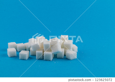 Cubes of white sugar stacked on a bright blue background 123625072