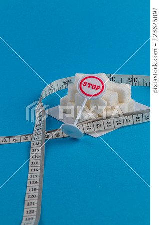 Preventing sugar overload with measuring tape and stop sign on blue background Preventing sugar overload with measuring tape and stop sign on blue background 123625092
