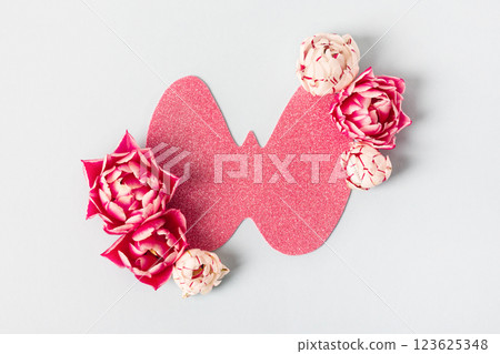 World Thyroid Day. Concept of thyroid disease and health. Pink Paper form of the thyroid gland on gray background with spring white and pink flowers tulips 123625348