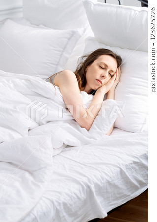 young woman sleeping on bed with white linen and air pillows. Correct regime and good sleep for female cycle young woman sleeping on bed with white linen and air pillows. Correct regime and good sleep for female cycle 123625726