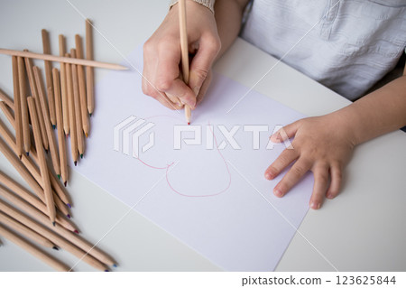 Child drawing heart with pencils on paper 123625844