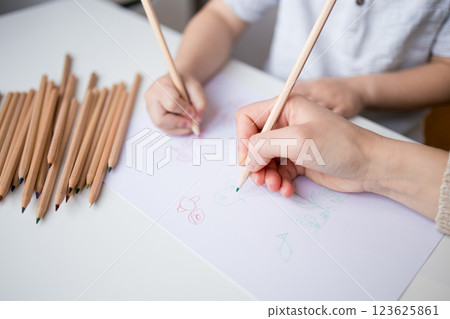 Young child and adult drawing with colored pencils on paper Young child and adult drawing with colored pencils on paper 123625861