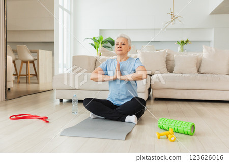 Yoga mindfulness meditation. Senior adult mature woman practicing yoga at home. Mid age old lady sitting in lotus pose on yoga mat meditating relaxing. Older middle aged woman doing breathing practice 123626016