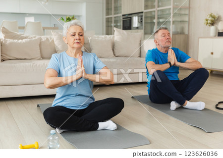 Yoga mindfulness meditation. Senior adult mature couple practicing yoga at home. Mid age old husband wife sitting in lotus pose on yoga mat meditating relaxing. Family doing breathing practice 123626036