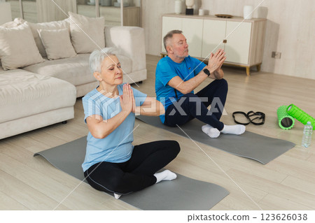 Yoga mindfulness meditation. Senior adult mature couple practicing yoga at home. Mid age old husband wife sitting in lotus pose on yoga mat meditating relaxing. Family doing breathing practice 123626038