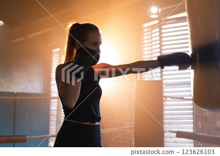 Women self defense girl power. Strong woman fighter training punches on boxing ring. Healthy strong girl punching boxing bag. Training day in boxing gym. Strength fit body workout training 123626103