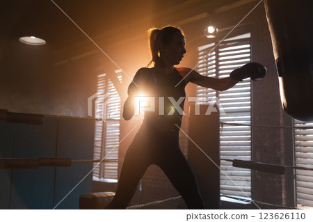Women self defense girl power. Strong woman fighter training punches on boxing ring. Healthy strong girl punching boxing bag. Training day in boxing gym. Strength fit body workout training 123626110