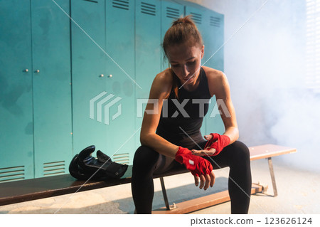 Women self defense girl power. Strong athlete woman fighter remove bandage after fight training on boxing ring. Strong girl tired wipes sweat after training session in gym. Strength fit body workout Women self defense girl power. Strong athlete woman fighter remove bandage after fight training on boxing ring. Strong girl tired wipes sweat after training session in gym. Strength fit body workout 123626124