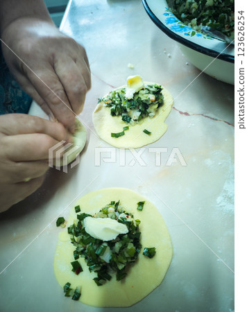 woman hands making homemade dumplings with jusai and onion at the kitchen table 123626254