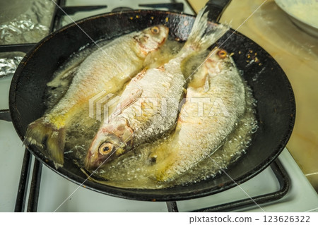 three whole freshwater fish frying with flour in old cast iron skillet three whole freshwater fish frying with flour in old cast iron skillet 123626322
