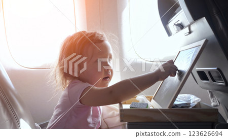 Little girl playing with folding tray table on airplane Little girl playing with folding tray table on airplane 123626694