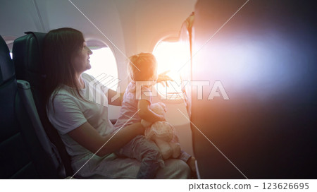 Mother fixing daughter's hair on airplane during flight 123626695