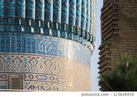 Blue mosaic covered tower juxtaposed with a traditional brick structure. Geometric turquoise tile patterns and craftsmanship, emphasizing cultural and historical significance of architectural site Blue mosaic covered tower juxtaposed with a traditional brick structure. Geometric turquoise tile patterns and craftsmanship, emphasizing cultural and historical significance of architectural site 123626958