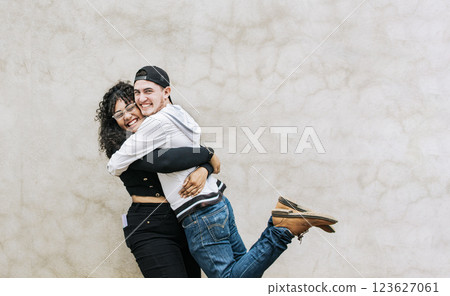 Two teenage friends embracing fraternally, Young happy couple embracing looking at camera outdoors, Teenage couple embracing happily looking at camera Two teenage friends embracing fraternally, Young happy couple embracing looking at camera outdoors, Teenage couple embracing happily looking at camera 123627061