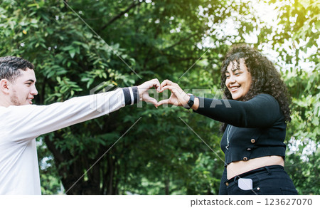 Young couple making heart shape with hands, Happy couple making heart shape with hands, Two friends outdoors making heart shape with hands 123627070
