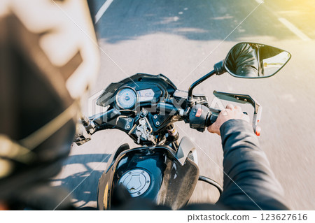 Close up of motorcyclist driving his motorbike on the street. View of hands of biker driving his motorbike 123627616