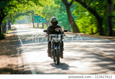 Male motorcyclist driving at high speed on the street. Motorcycle driver at full speed on the highway. 123627622