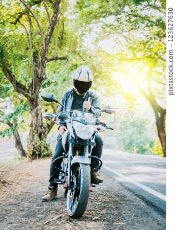 Motorcyclist in safety helmet with thumb up on the road. Biker wearing safety helmet with thumb up on the road Motorcyclist in safety helmet with thumb up on the road. Biker wearing safety helmet with thumb up on the road 123627630