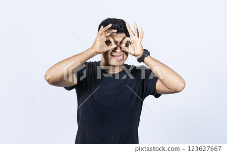 Curious man making binoculars gesture, Guy on isolated background making binoculars gesture, Man making binoculars gesture, man using his fists as binoculars Curious man making binoculars gesture, Guy on isolated background making binoculars gesture, Man making binoculars gesture, man using his fists as binoculars 123627667