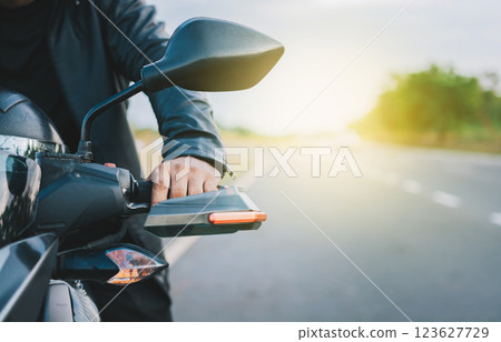 Hands of a motorcyclist on the handlebars on the road. Close up of hands of biker on the handlebars of a motorcycle outdoors. Motorbike speeding concept 123627729