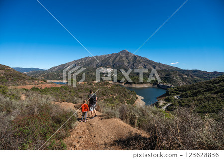 Father and son hiking scenic trail in mountainous landscape with reservoir view, La Concepcion 123628836