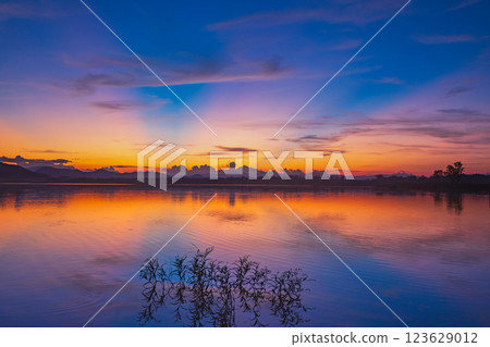 Landscape of mountains and lake at sunset and clouds reflected in the water. 123629012