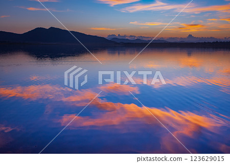 Landscape of mountains and lake at sunset and clouds reflected in the water. 123629015