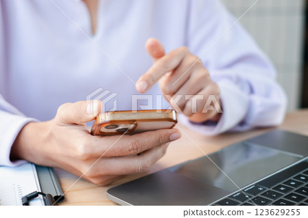 Hands interacting with a smartphone and laptop, showcasing technology use in a professional environment. Hands interacting with a smartphone and laptop, showcasing technology use in a professional environment. 123629255