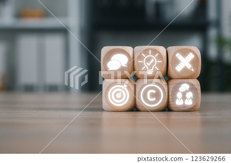 Wooden blocks with corporate icons representing business identity, branding, and strategy in a modern office setting. 123629266