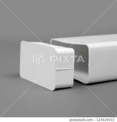 White plastic pipe with a plug on a gray background. Rectangular shape. 123629553