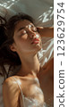 A woman is laying on a bed with her eyes closed 123629754