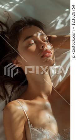 A woman is laying on a bed with her eyes closed A woman is laying on a bed with her eyes closed 123629754