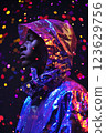 A person is wearing a shiny, metallic jacket and standing in front of a bright. Cyberpunk concept 123629756