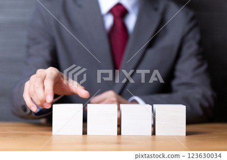Four white wooden blocks and a middle-aged male businessman in a suit 123630034