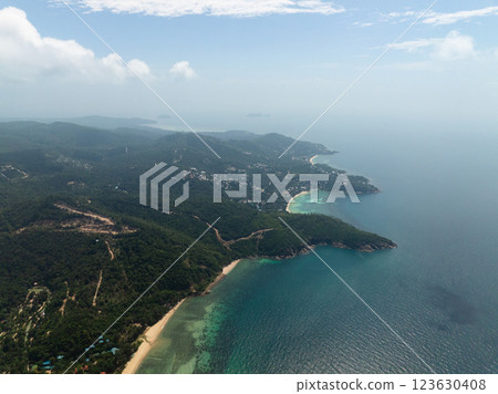 Aerial view of a lush coastline with turquoise waters and white sandy beaches under a bright blue sky. Ko Pha Ngan, Thailand. Aerial view of a lush coastline with turquoise waters and white sandy beaches under a bright blue sky. Ko Pha Ngan, Thailand. 123630408