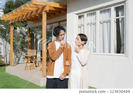 A couple thinking in front of their house A couple thinking in front of their house 123630489