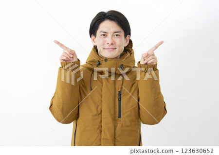 A man wearing a down jacket pointing left and right on a white background A man wearing a down jacket pointing left and right on a white background 123630652