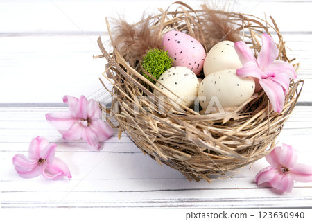 Easter nest with speckled eggs, moss and pink flowers. Easter nest with speckled eggs, moss and pink flowers. 123630940