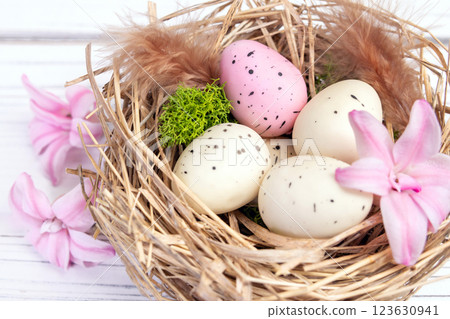 Easter nest with speckled eggs, moss and pink flowers. Easter nest with speckled eggs, moss and pink flowers. 123630941