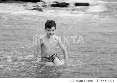 Teen boy is sitting on the Black sand beach in Hawaii. Teen boy is sitting on the Black sand beach in Hawaii. 123630993